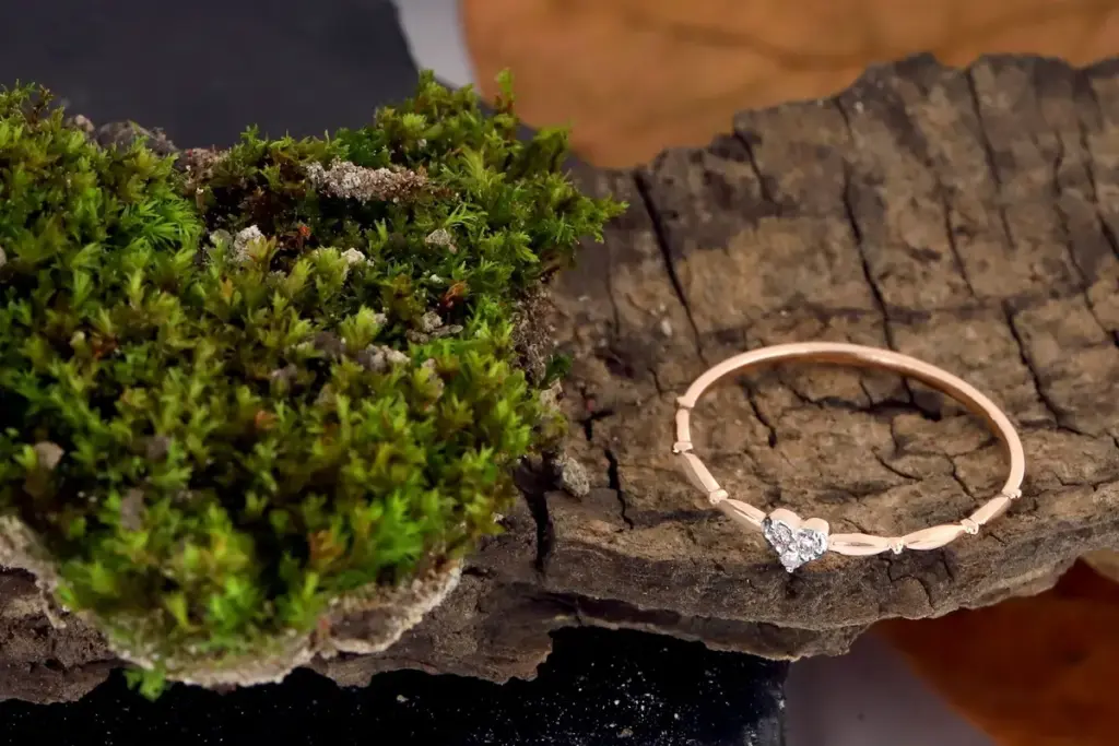 Anillo fino de oro rosa con un corazón de piedras sobre una corteza