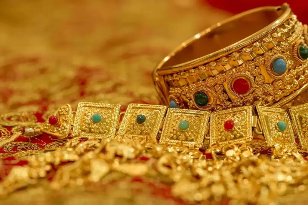 Brazaletes y joyas de oro sobre una tela roja y dorada