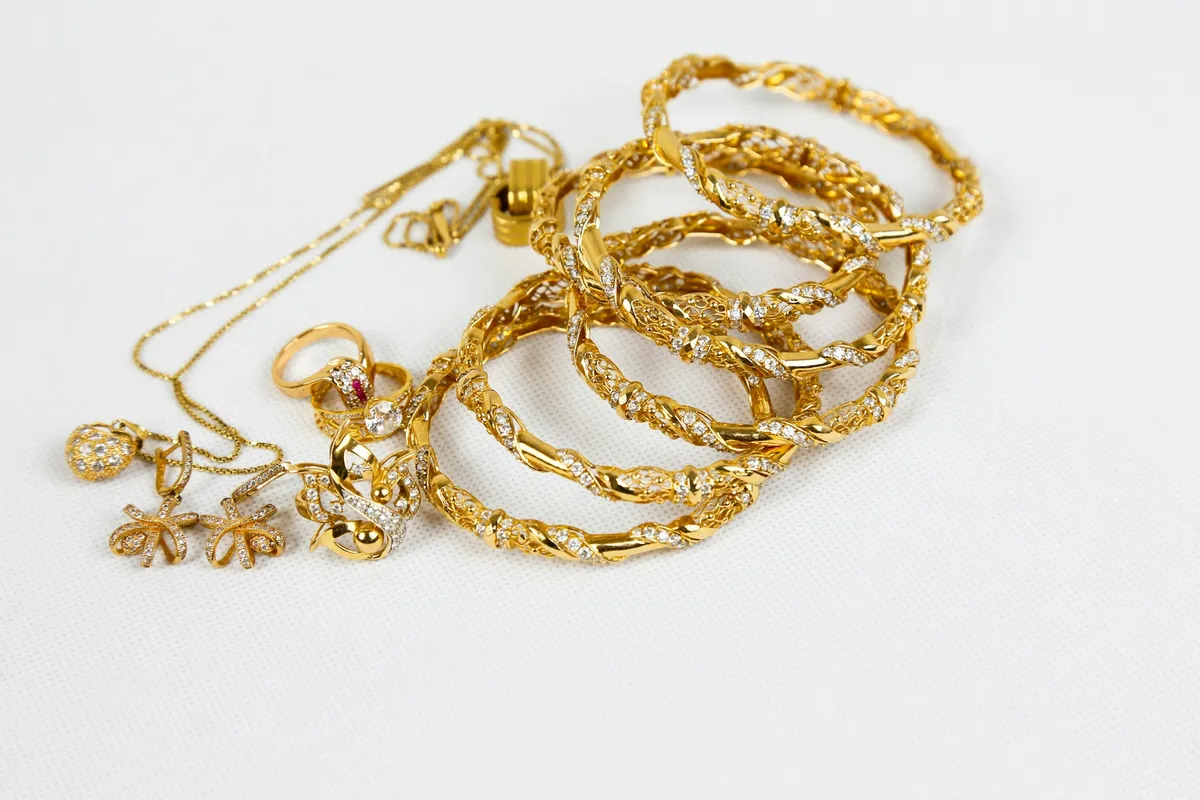 Pulseras, cadena, anillos y pendientes de oro amontonados sobre una superficie blanca