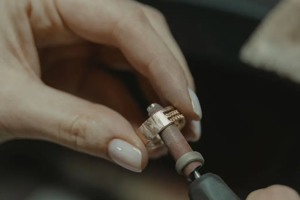 Manos de joyero puliendo un anillo de oro en el taller