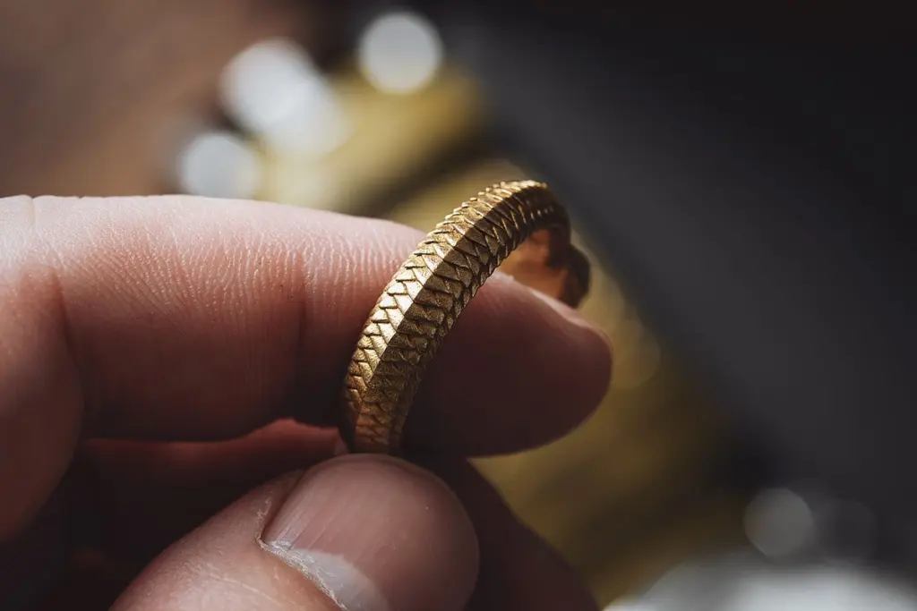 Mano sosteniendo un anillo de oro labrado