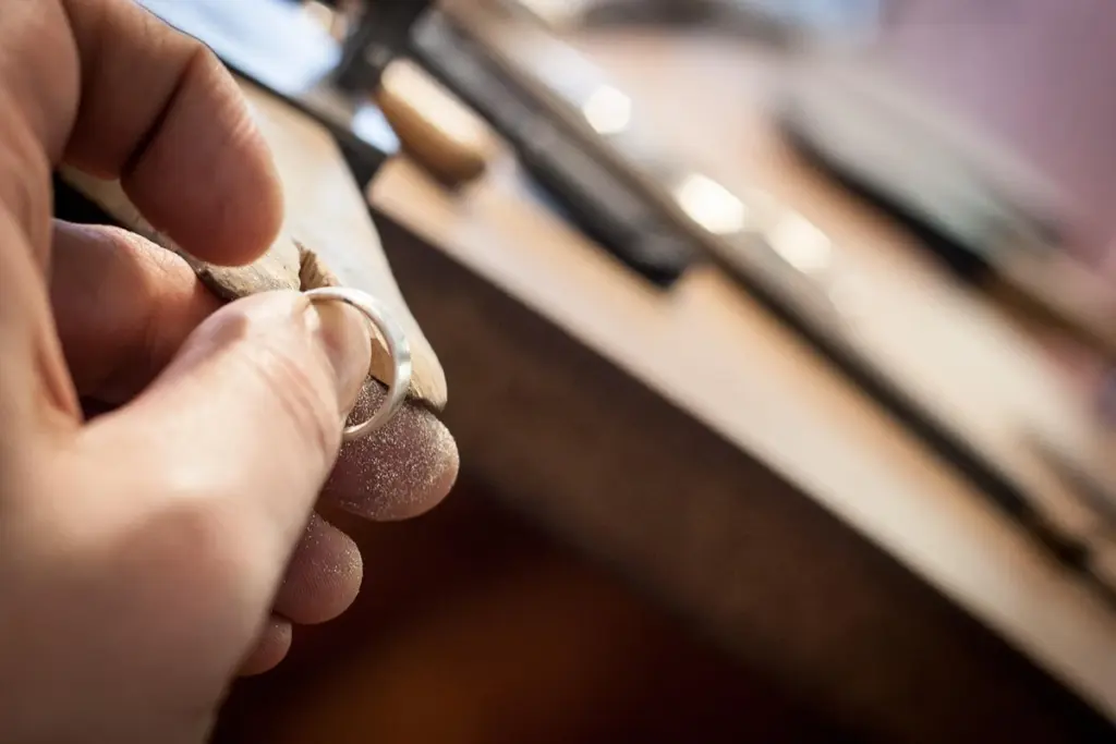 Manos de un orfebre sujetando un anillo en su banco de trabajo